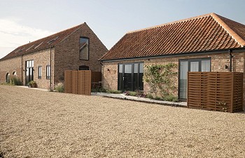 seen from the back of the plot, two barn conversions stand competed behind a gravel driveway